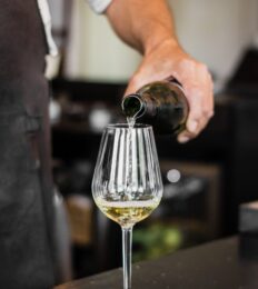 vertical-shot-bartender-pouring-wine-into-glass